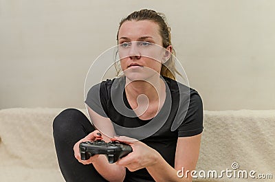 A young woman plays a game console with a joystick Stock Photo
