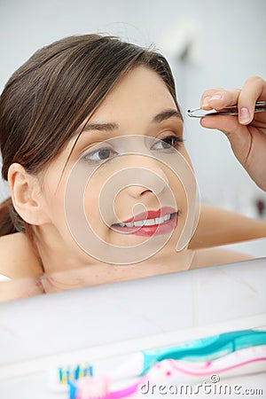 Young woman plucking her eyebrows Stock Photo