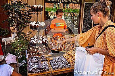 Young woman pointing at Gothenburg cakes on sale on outside food stall in Gothenburg, Sweden Editorial Stock Photo