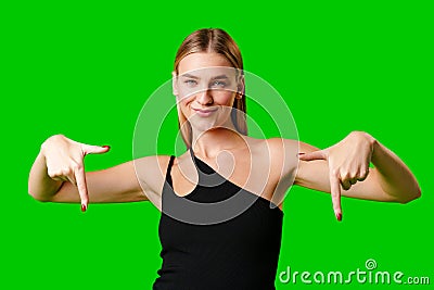 Young Woman Pointing at Something against green background Stock Photo