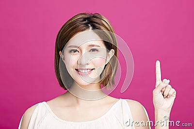 Woman pointing to somewhere, isolated on pink background Stock Photo