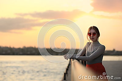 Young woman posing near railing on waterfront Stock Photo