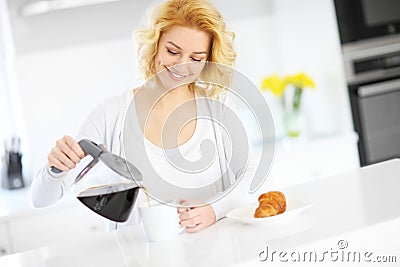 Young woman pouring coffee in the kitchen Stock Photo