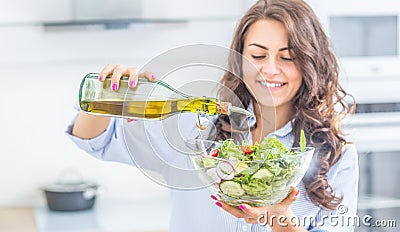Young woman pouring olive oil in to the salad. Healthy lifestyle eating concept Stock Photo