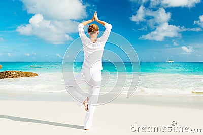 Young woman practices yoga on the beach Stock Photo