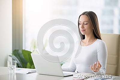 Young woman practicing meditation at the office desk Stock Photo