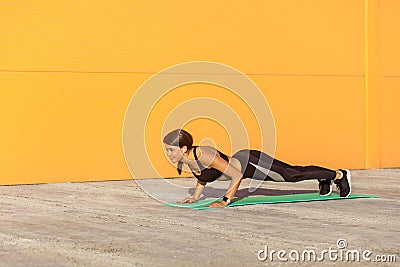 Young woman practicing yoga, doing four limbed staff, push ups or press ups exercise, chaturanga dandasana pose, working out, Stock Photo