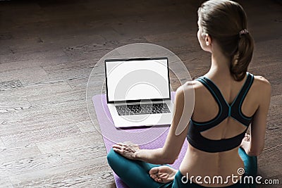 Young woman practicing yoga at home, online video training class, girl doing exercises and meditate Stock Photo
