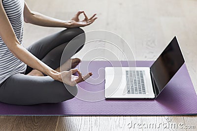 Young woman practicing yoga at home. Online video training. Girl doing exercises and meditate. Stock Photo