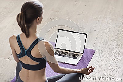 Young woman practicing yoga at home. Online video training. Girl doing exercises and meditate. Stock Photo