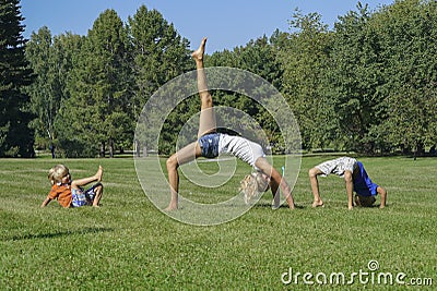 Young woman practicing yoga with kids on green grass Stock Photo