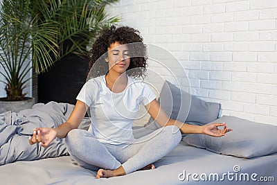 Young woman practicing yoga meditation on her bed Stock Photo