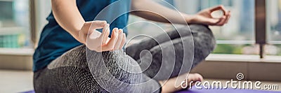 Young woman is practicing yoga in the morning on her balcony with a panoramic view of the city and skyscrapers BANNER, long format Stock Photo