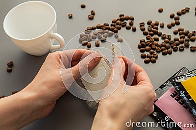 Young woman preparing a modern filter coffee in a drip bag at home. Step 2: Open drip bag Stock Photo