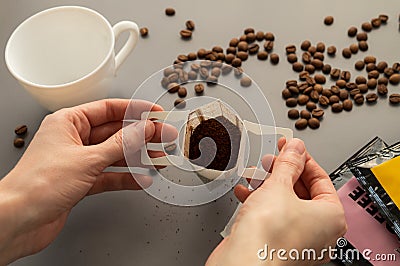 Young woman preparing a modern filter coffee in a drip bag at home. Step 2: Open drip bag Stock Photo
