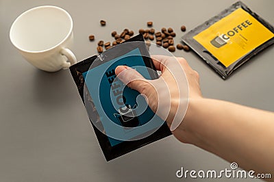 A young woman preparing a modern filter coffee in a drip bag at home. Step 1: Open the package Stock Photo