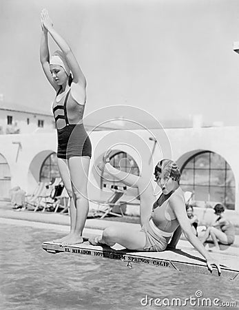 Young woman preparing to dive from a diving platform with another woman sitting beside her Stock Photo