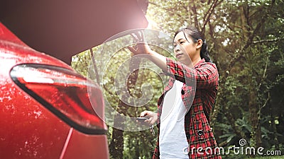 A young woman pressing the button to close the trunk of the car. Automatically opening and closing the trunk of a car. Stock Photo