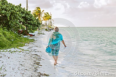 Young woman walking on the beach along the ocean Stock Photo