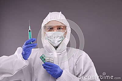 Woman in protective costume holds a syringe Stock Photo