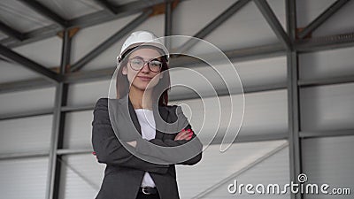A young woman in a protective helmet and shows a thumb at a construction site. The boss in a suit looks at the camera. Stock Photo