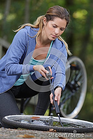 young woman pumps up tires bike Stock Photo