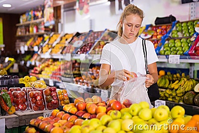 Young woman purchaser choosing apples in grocery Stock Photo