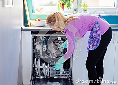 Young woman putting dirty dishes to dishwasher Stock Photo