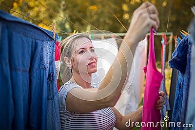 Young woman putting laundry on a rope in her garden Stock Photo