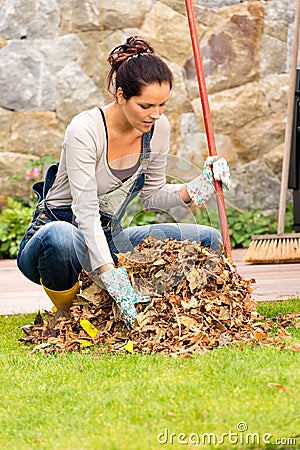 Young woman raking dry leaves autumn backyard Stock Photo