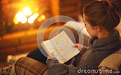 Young woman reading a book by the fireplace on a winter evenin Stock Photo