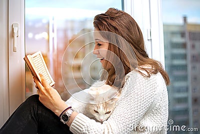 Young woman is reading a book with her cat Stock Photo