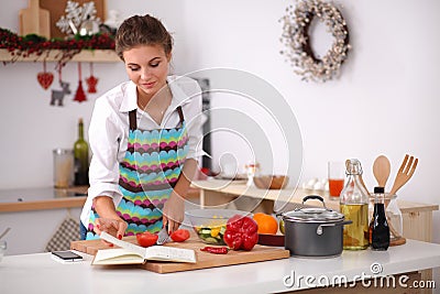 Young woman reading cookbook in the kitchen, Stock Photo