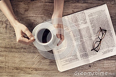 Young woman reading newspaper and holding coffee cup Stock Photo