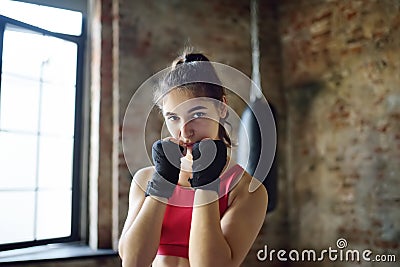 Young woman ready for hits punching bag during a boxing training. Female boxer doing fitness Stock Photo