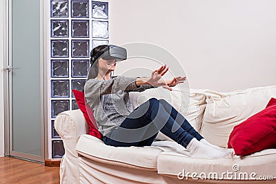 Young woman realxing on the couch and having fun playing a virtual reality simulation Stock Photo