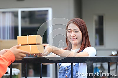 Young woman receiving parcel from delivery man bringing some pac Stock Photo