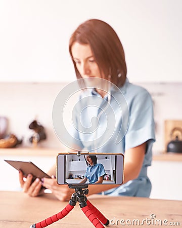 Young woman record video at kitchen. Self portrait. Blogger selfie video Stock Photo