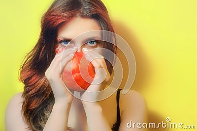 A young woman with a red garnet, copy space. Female portrait and red fruit. Girl with pomegranate on a yellow background Stock Photo