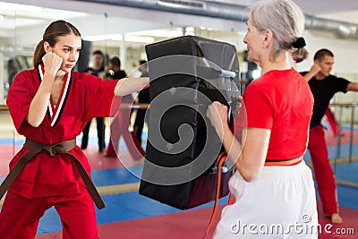 Young woman in red kimono launching blows on punch shield Stock Photo