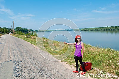 Young woman with a red suitcase hitching a lift Stock Photo