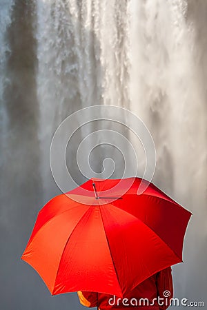 Young Woman WIth Red Umbrella In Front of a Waterfall Stock Photo