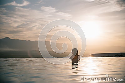 young woman relaxing in beautiful pool at sunset Stock Photo