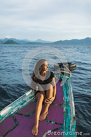 Young woman relaxing on boat at sunset in ocean Stock Photo