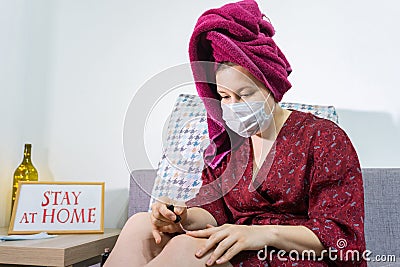 Young woman relaxing at home and paint nails. Cozy time at home. Self time and Coronavirus outbreak quarantin concept Stock Photo