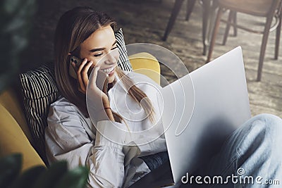 Young woman relaxing at home, watching movies on laptop, streaming tv series, talking to friends on smartphone. Stock Photo