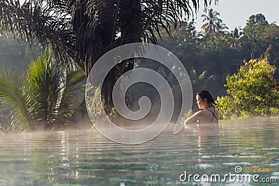 A young woman relaxing in an infinity pool Stock Photo