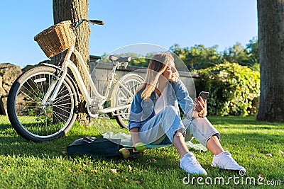 Young woman relaxing sitting on grass in park using smartphone Stock Photo