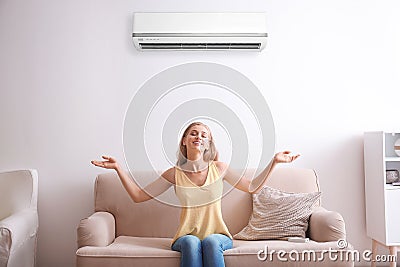 Young woman relaxing under air conditioner Stock Photo