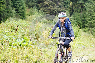 Young woman riding bicycle in mountain forest Stock Photo